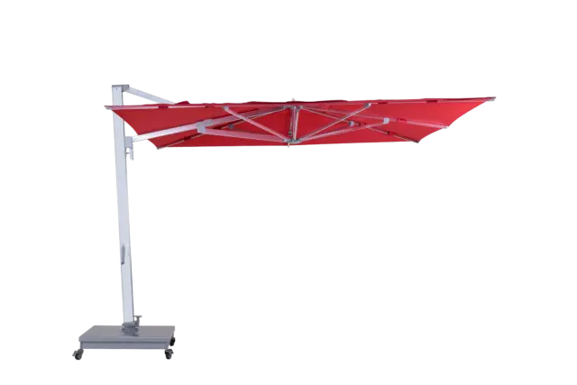 A fully open, red Aman cantilever umbrella shown from the side, highlighting its expansive square canopy and robust side-post aluminum frame on a wheeled base.