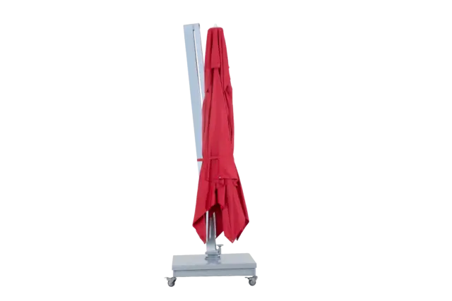 The red Aman patio umbrella in its collapsed and folded upright position, showcasing a compact profile for easy storage.