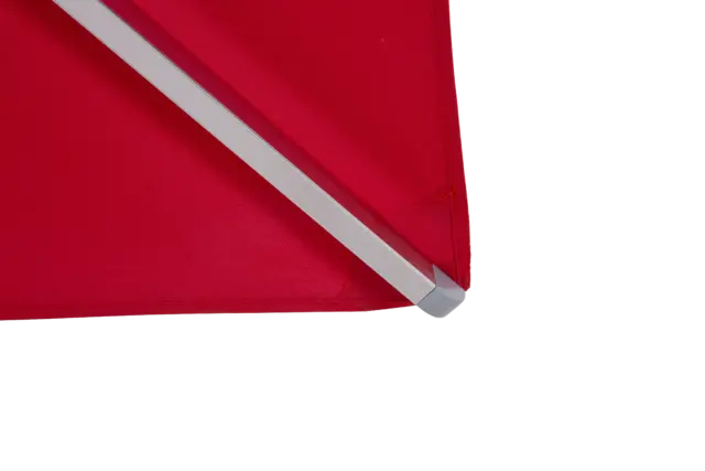 A close-up of the corner of the red Aman umbrella, showcasing the high-quality, weather-resistant fabric, precise stitching, and durable rib end cap.