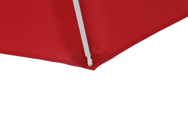 A close-up image of the corner of the red Bossa Nova center-pole market umbrella's canopy, highlighting the reinforced pocket where the white frame arm connects.