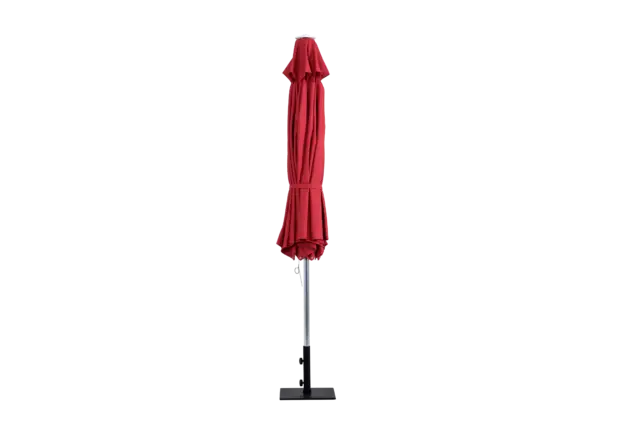 The red Bossa Nova center-pole market umbrella in a closed position, secured with a tie, and shown with its black square freestanding base.