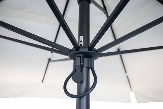 A close-up, underneath view of the Istanbul center pole market umbrella's hub, showing the durable black frame and simple rope pulley lift system for easy opening.