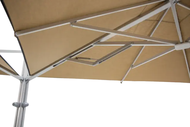 An underneath close-up of the M2 Maximus umbrella, showing the robust aluminum frame and the intricate support structure holding the tan-colored canopy fabric.