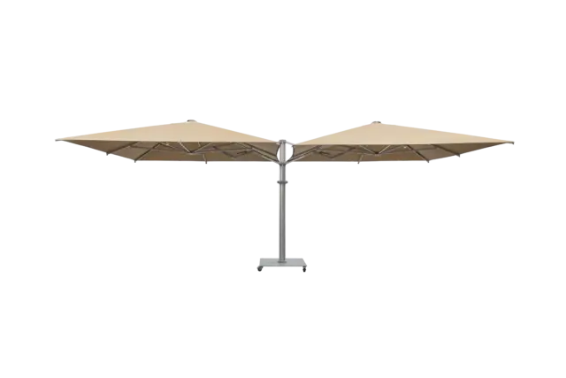 A full-view product shot of the M2 Maximus, a large, tan double-headed parasol with a central aluminum pole and a mobile wheeled base, against a neutral background.