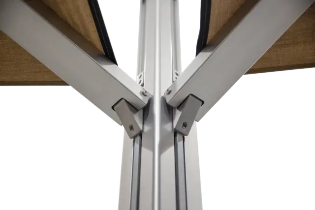 A shot of the central joint on the M2 Maximus umbrella where the dual canopies attach to the main pole, viewed from a low angle against a blue sky.