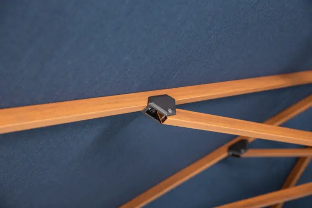 Close-up of the internal structure of an open Piazza center pole umbrella, highlighting the wood-tone ribs and connection points supporting the navy canopy.